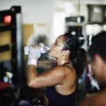 Foto: 1 de 1 Foto de mulher suada bebendo água na academia durante descanso entr