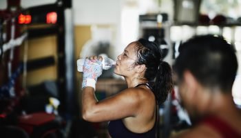 Foto: 1 de 1 Foto de mulher suada bebendo água na academia durante descanso entr