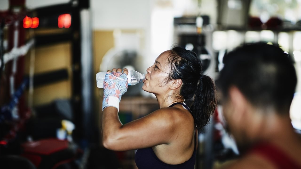 Suor-na-academia-1 Foto: 1 de 1 Foto de mulher suada bebendo água na academia durante descanso entr