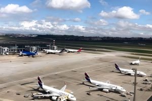 Pista de aeroporto com aeronaves estacionadas, o céu está azul com nuvens — Foto
