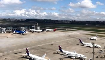 Pista de aeroporto com aeronaves estacionadas, o céu está azul com nuvens — Foto