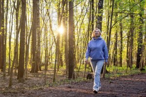 Mulher caminhando em um parque iluminado pelo sol ao pôr do sol na primavera — F