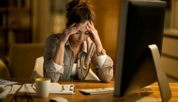 Foto colorida de mulher em frente à mesa, com as mãos na cabeça, insinuan — Foto