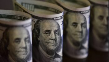 Foto: 1 de 1 Imagem colorida de maços de notas de dólar norte-americano - Foto: