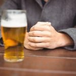 Mid section of man sitting in bar with glass of beer on table