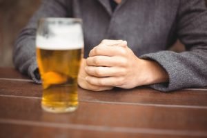 Mid section of man sitting in bar with glass of beer on table