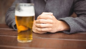 Mid section of man sitting in bar with glass of beer on table